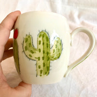 Handmade pottery mug with a hand painted cactus and succulent design pattern.