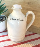 Contenant pour le sirop blanc fait à la main en porcealineWhite Maple syrup pitcher handmade pottery with french or english inscription on white background